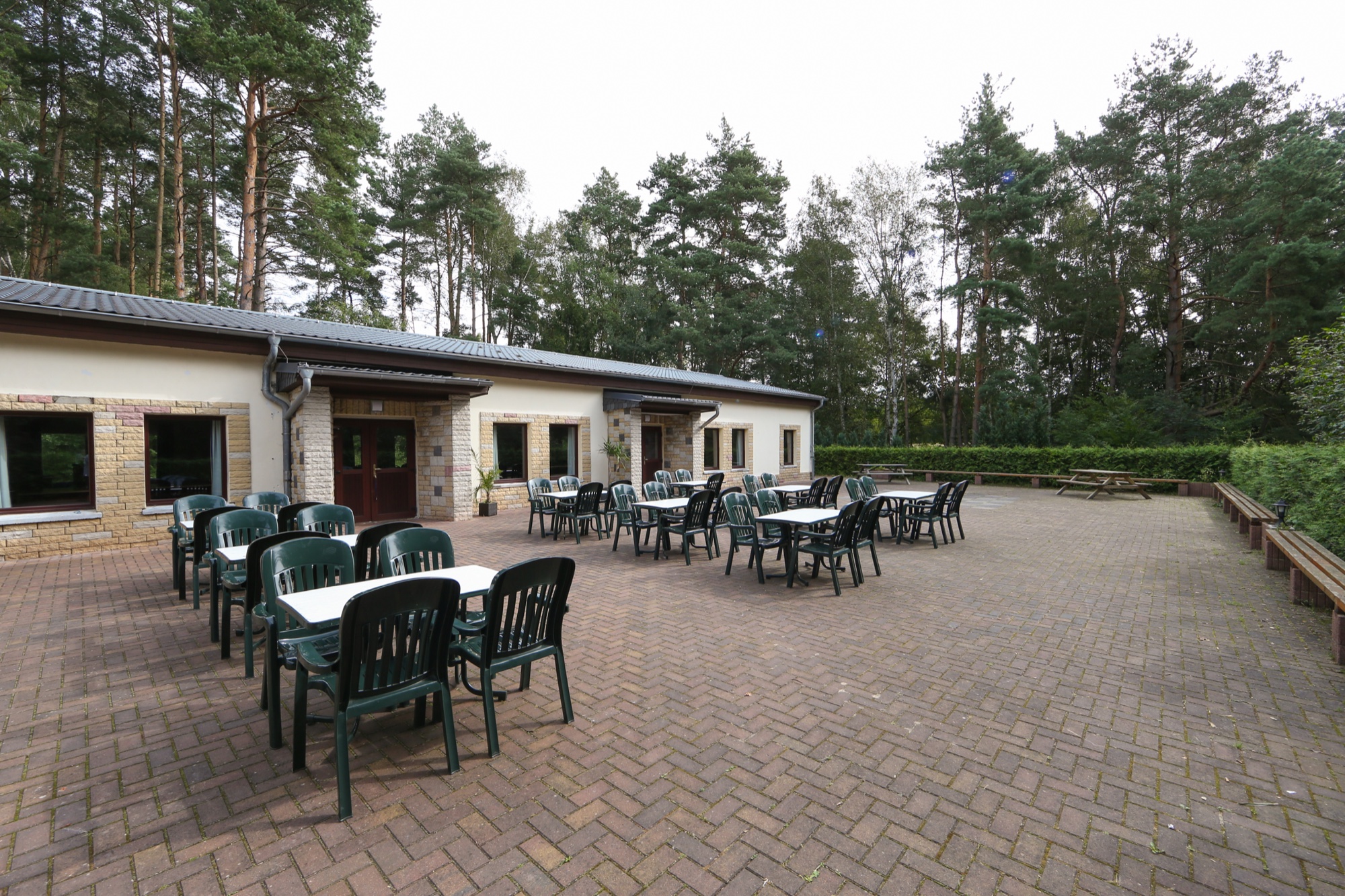 Gro&szlig;e Terrasse mit Tischen und St&uuml;hlen am Waldrand