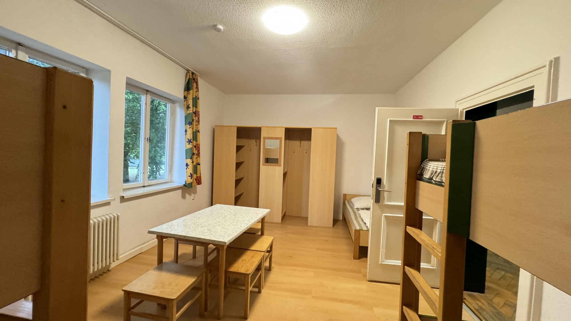 Mehrbettzimmer mit Etagenbetten, Schr&auml;nken und Sitzgruppe