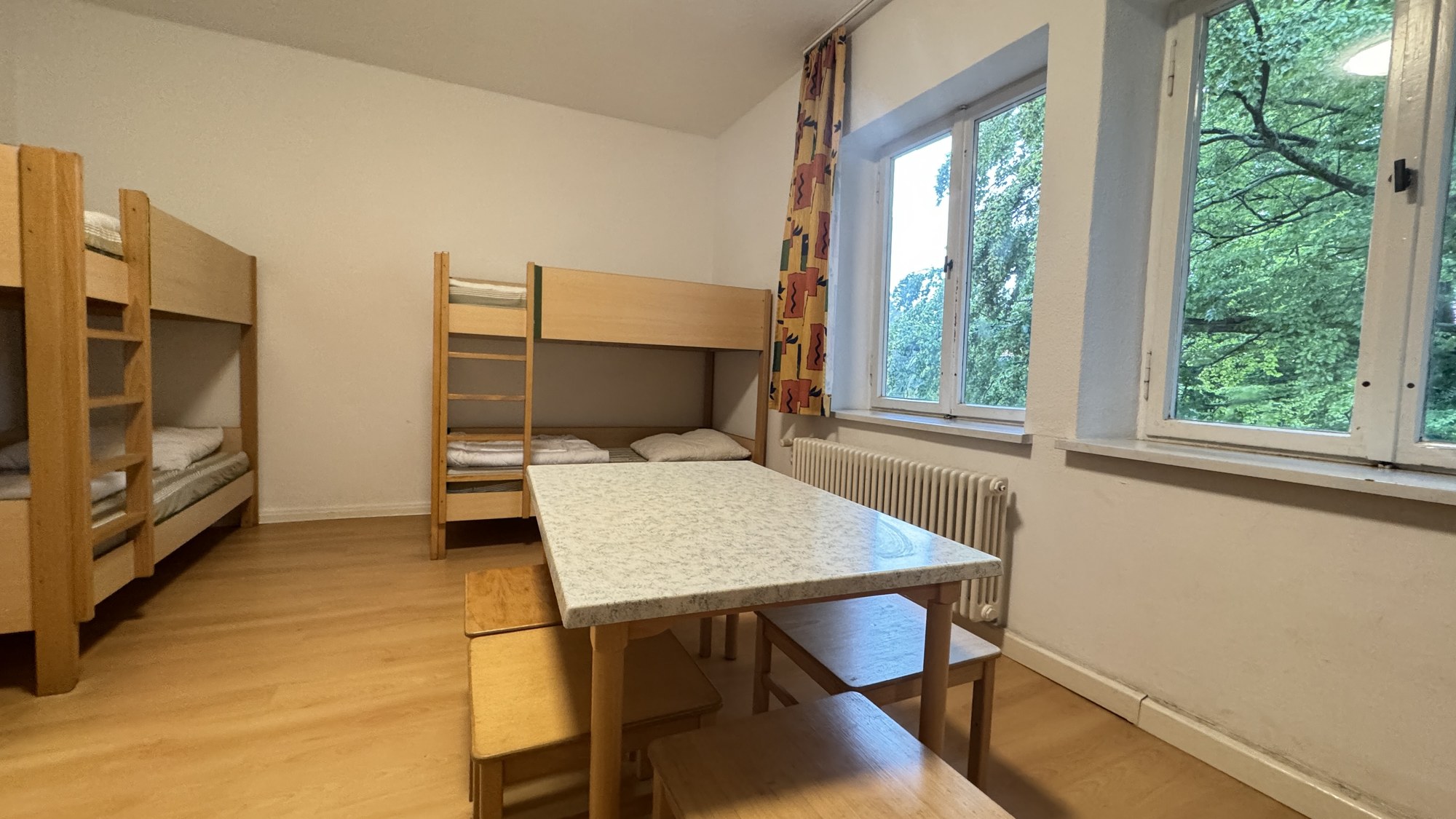 Mehrbettzimmer mit Etagenbetten und Blick ins Gr&uuml;ne